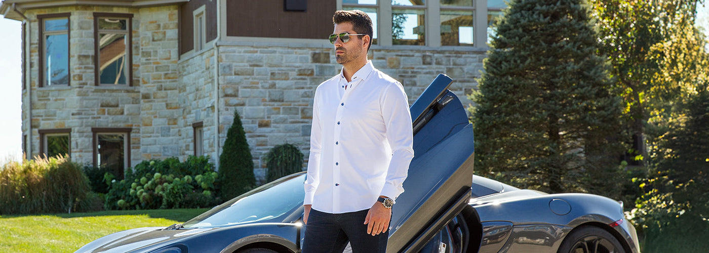 Modèle homme portant une surchemise bleu clair dans un décor urbain moderne avec structures métalliques. Styles intemporels Au Noir disponibles toute l'année avec coupes élégantes et design signature.