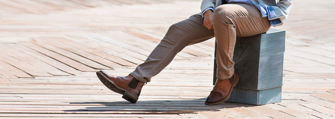 Vue rapprochée de souliers noirs modernes portés avec bermuda devant une voiture sportive. Souliers Au Noir élégants combinant style urbain et confort.