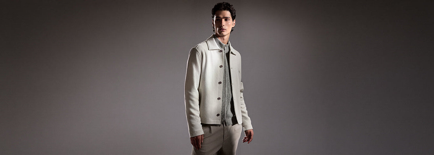 Homme portant une veste écrue sur un tricot gris avec pantalon beige, tenue masculine moderne de la collection Robert Barakett.