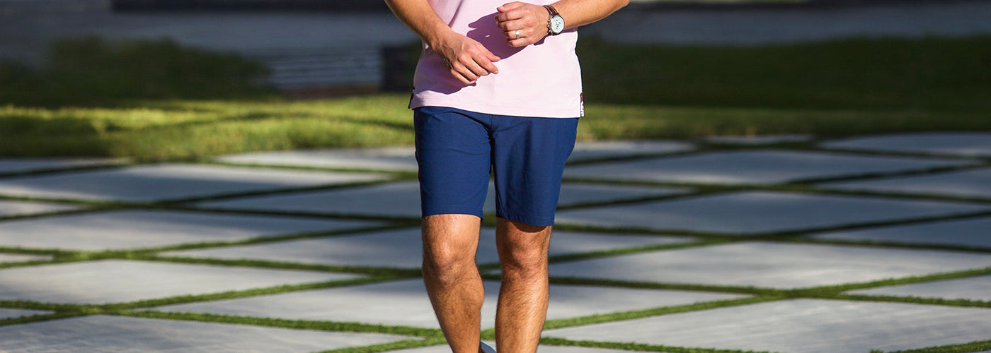 Modèle homme assis sur une voiture sportive noire portant un bermuda clair et chemise à motif. Bermudas Au Noir stylés et confortables parfaits pour la saison estivale.