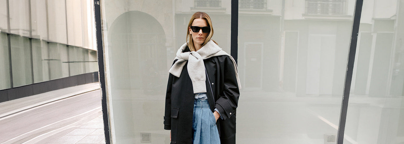 Écharpe gris clair nouée sur un manteau noir avec lunettes de soleil, accessoires mode pour femme au style urbain.