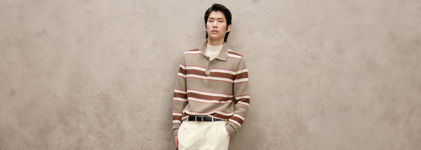 Homme portant un polo en tricot rayé beige et brun avec pantalon clair, look masculin de la collection BOSS.