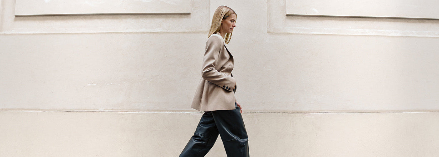 Femme portant un veston beige avec pantalon noir dans un décor architectural clair, look féminin de la collection InWear.