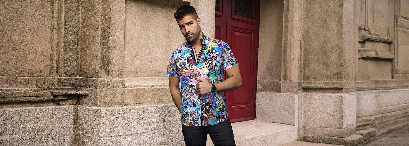 Modèle homme portant une chemise M.C. à motif tropical devant une résidence luxueuse entourée de palmiers. Chemises Au Noir légères et stylées idéales pour un look estival sophistiqué.