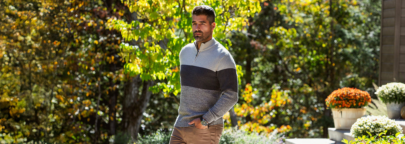 Modèle homme portant un Knit sweater mérino bicolore dans un décor automnal avec arbres colorés. Chandails Au Noir en laine mérino offrant chaleur, confort et élégance.