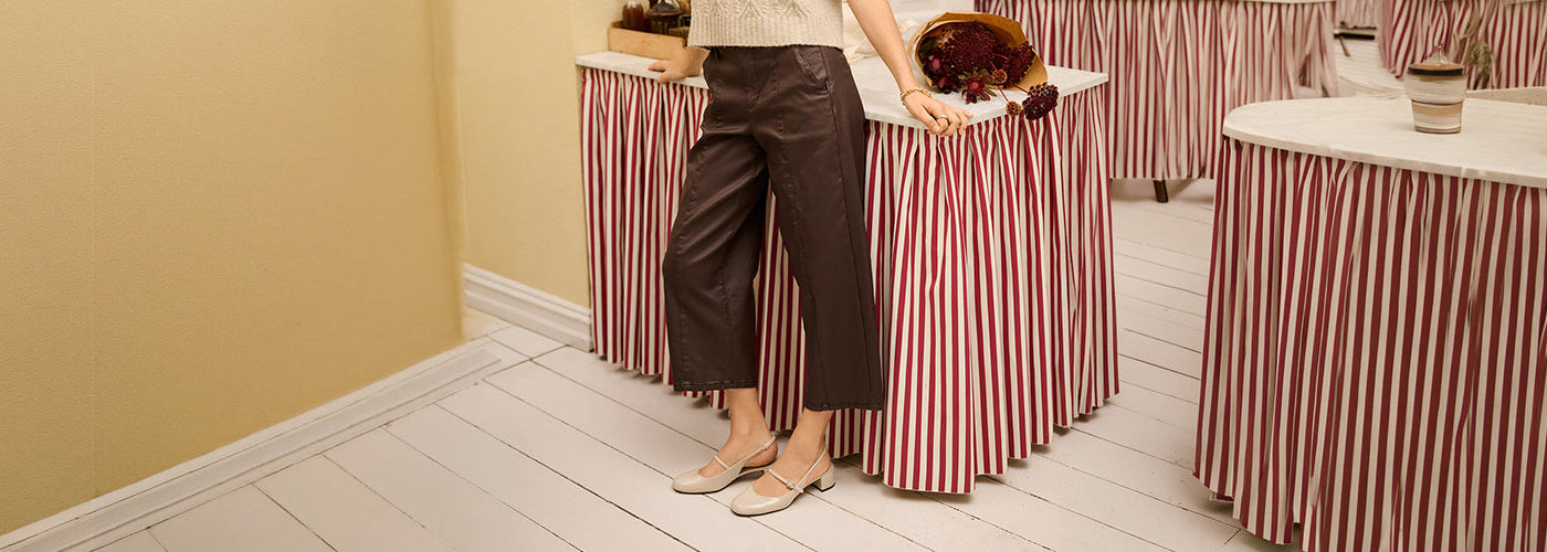 Pantalon brun à jambe large et longueur cheville associé à un haut crème et des ballerines, tenue féminine moderne.