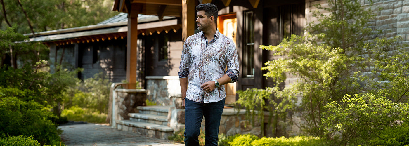 Chemise à imprimé abstrait dans des tons neutres portée avec un jeans foncé, style homme moderne en extérieur.
