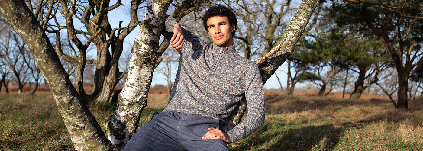 Tricot gris à col montant zippé dans un décor naturel, un essentiel moderne de la garde robe masculine.