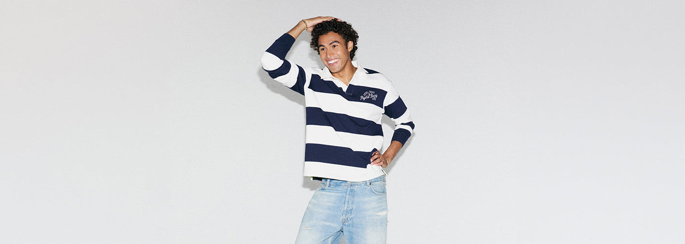Polo rugby marine et blanc à larges rayures, associé à un jeans bleu pâle pour un look homme décontracté.