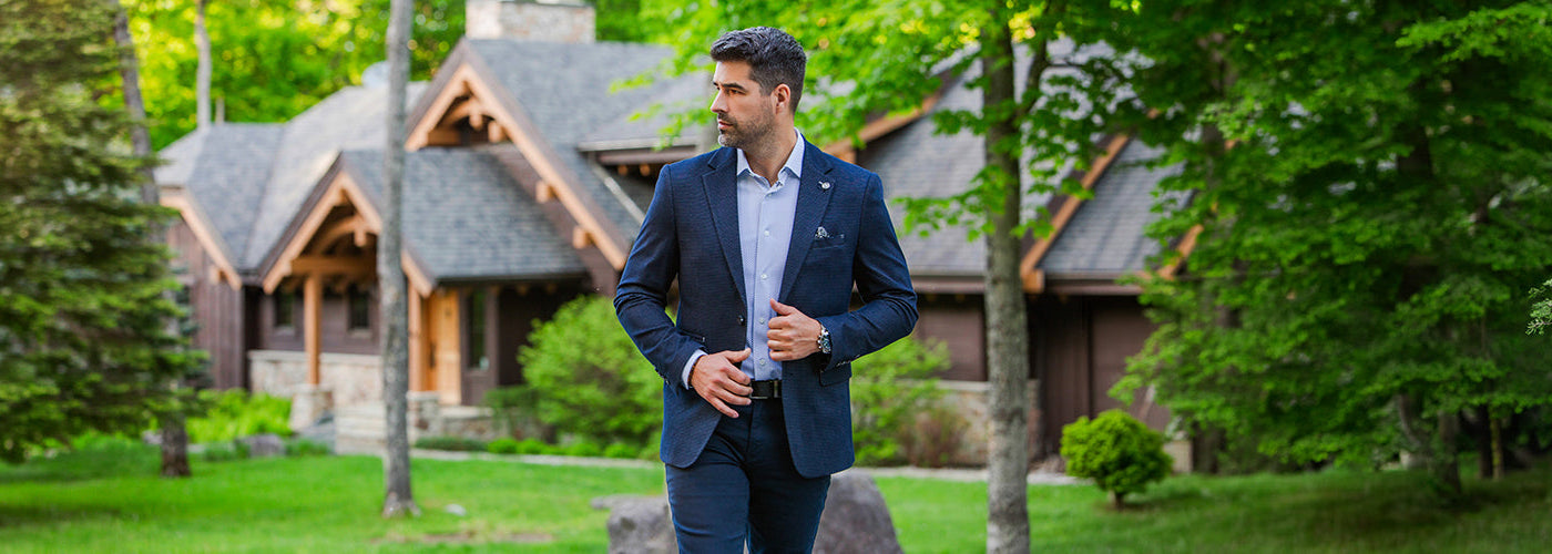 Modèle homme élégant portant un Blazer rayé devant une voiture sportive noire dans un décor tropical. Collection complète Au Noir avec styles modernes, vêtements premium et looks raffinés pour hommes.