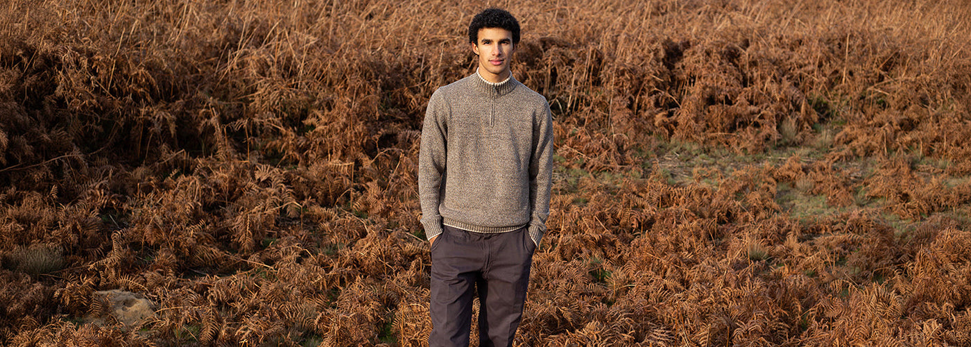 Homme portant un tricot gris à col montant zippé dans un paysage automnal, look décontracté de la collection Fellows United.