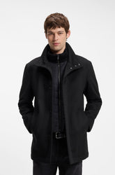Vue de face d’un manteau d’hiver noir avec col montant, boutons-pression et panneau matelassé pour homme par HUGO BOSS