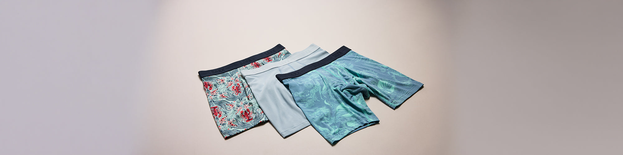 Trois sous vêtements hommes aux motifs variés présentés sur fond neutre. Collection sous vêtements hommes confortables et sous vêtements modernes.