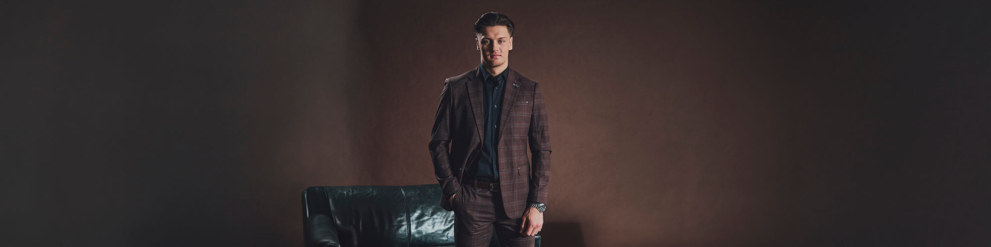 Visuel élégant de la collaboration Au Noir x Zachary Bolduc, joueur de hockey montréalais, en veston brun texturé devant un décor sombre et raffiné.