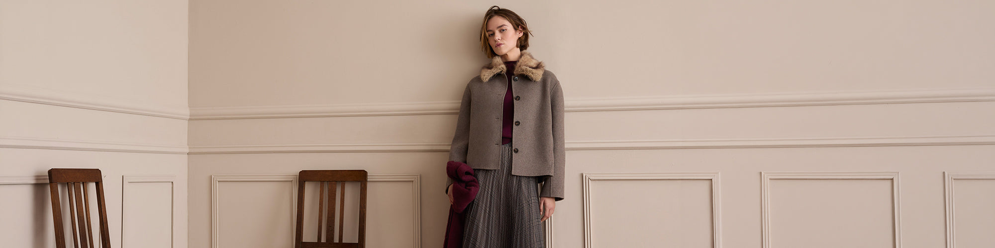 Femme portant une veste courte taupe à col en fausse fourrure, jupe midi à carreaux et accessoires bordeaux, look automne OUI pour femme.