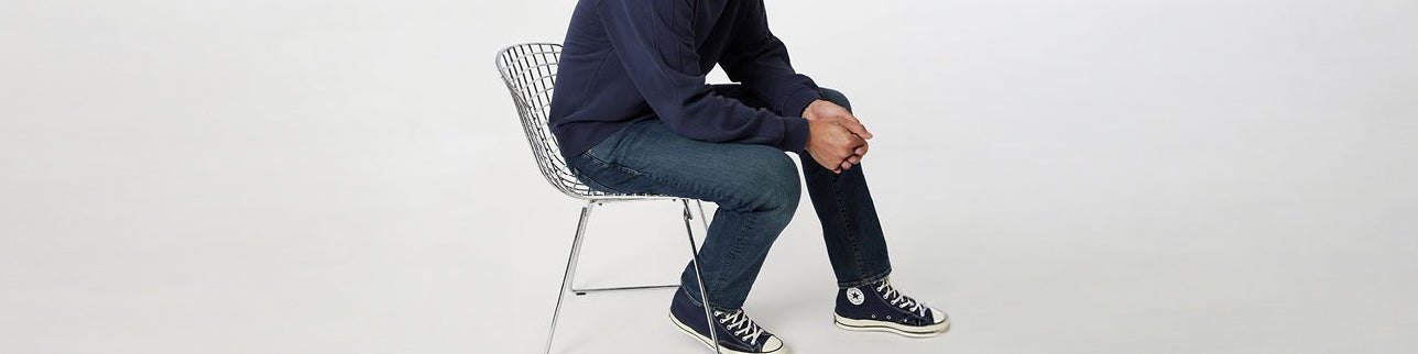Dark blue jeans paired with a navy top and high top sneakers, versatile casual men’s outfit.