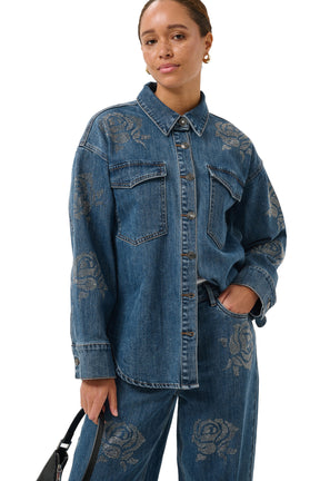 Vue avant en angle du blouse manches longues en denim bleu avec poches à rabat et roses en strass pour femme par Kaffe