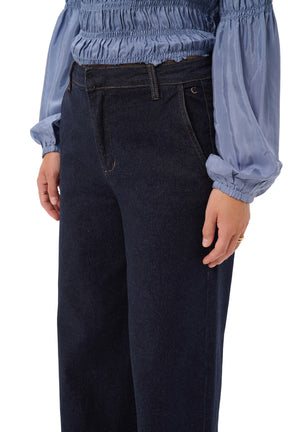 Cream women's dark indigo jean waistband, front pocket, wide-leg jeans loops, and gold stitching, close-up