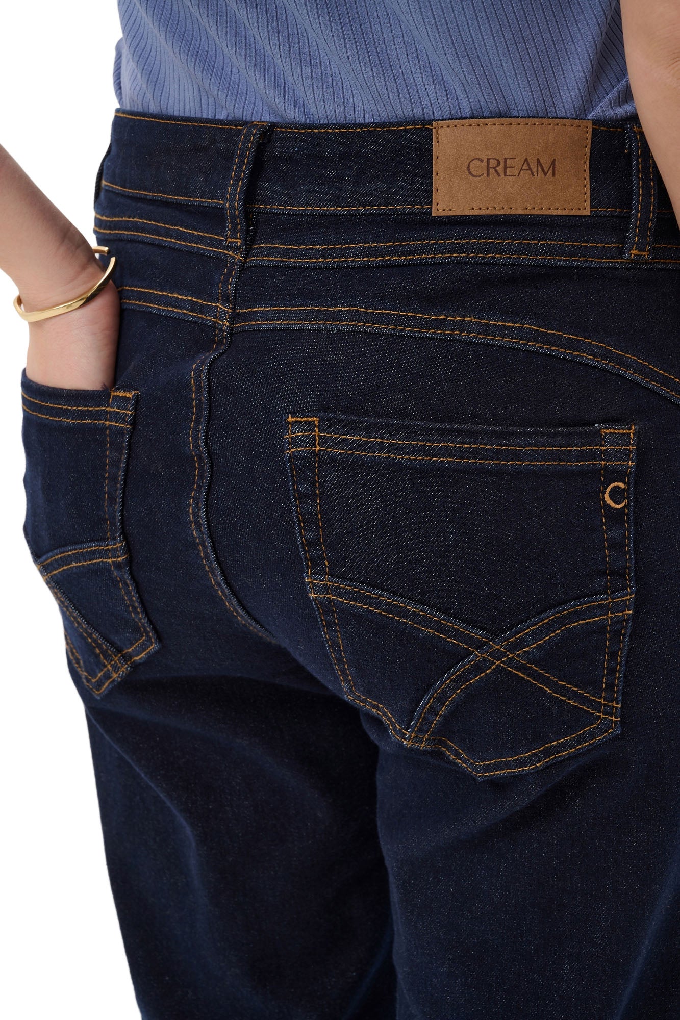 Poches arrière d’un jean droit indigo foncé avec surpiqûres tan et écusson CREAM pour femme, en gros plan