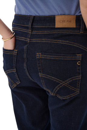 Poches arrière d’un jean droit indigo foncé avec surpiqûres tan et écusson CREAM pour femme, en gros plan