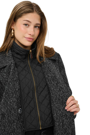 Cream women's black quilted zip bib under the black and white herringbone coat lapels, close view