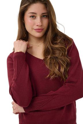 Cream women's burgundy V-neck knit long-sleeve knit sweater showing braided neckline and sleeve texture, close view