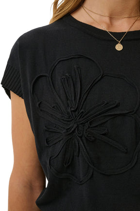 Cream women's black knit Short-sleeve T-Shirt showing ribbed crew neck, sleeve cuff, and raised floral appliqué, close-up