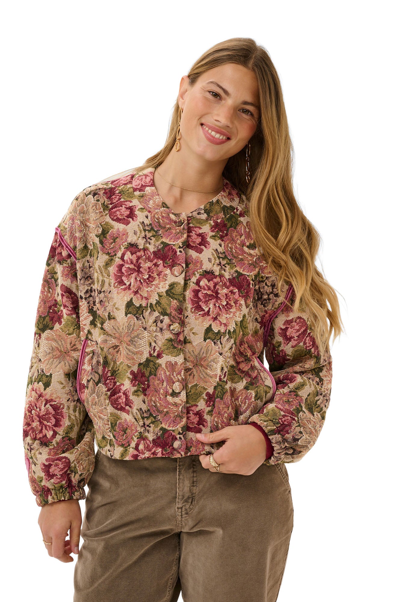 Cream women's front model in cropped beige floral jacket with buttons, long sleeves, and pink piping