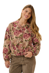 Cream women's front model in cropped beige floral jacket with buttons, long sleeves, and pink piping