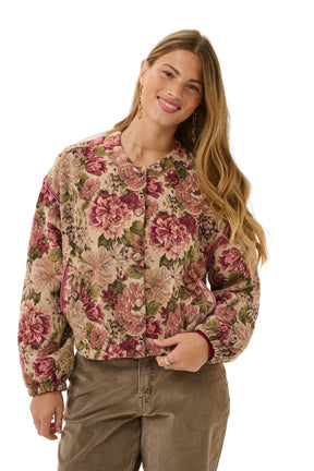 Cream women's front model in cropped beige floral jacket with buttons, long sleeves, and pink piping