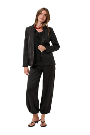 Women's full front model view of black satin-look jogger pants styled with a black blazer by Cream