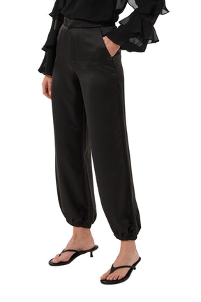Cream women's black satin-look jogger pants with side pocket and gathered elastic hems, front view