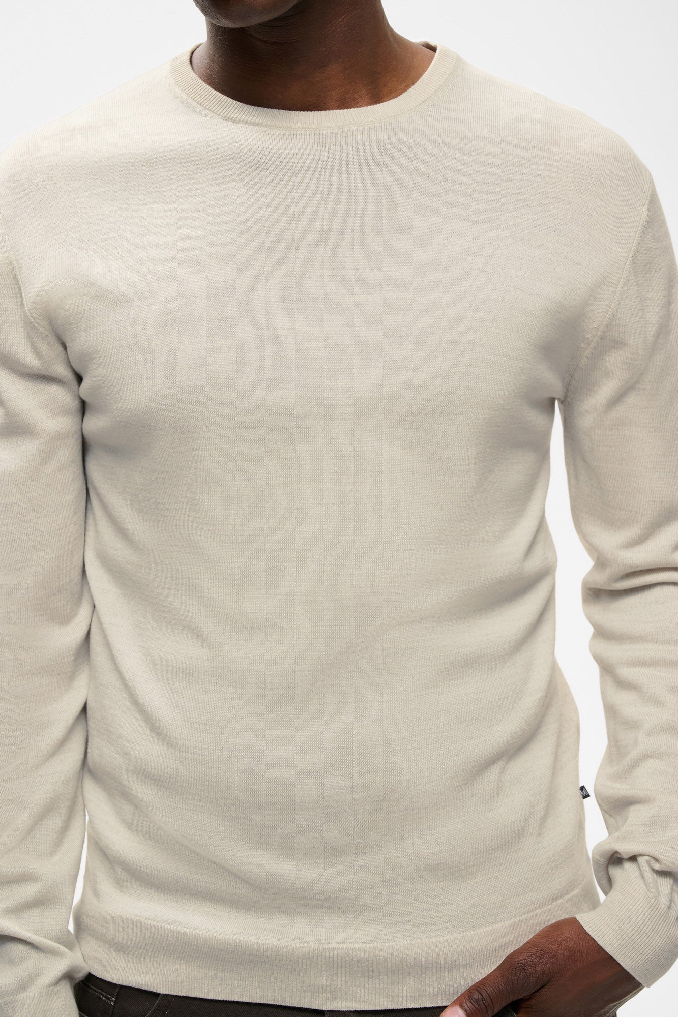 Men's close front view of the light beige knit long-sleeve knit sweater showing ribbed crewneck, cuffs, and hem by Matinique