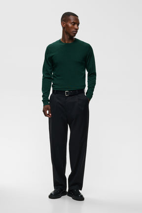 Vue avant pleine longueur du chandail manches longues en tricot vert foncé porté avec pantalon noir pour homme par Matinique