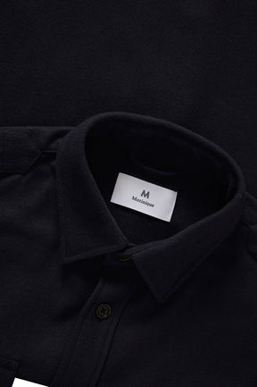 Close-up of men's black overshirt collar, button placket, brushed texture, and inner label by Matinique