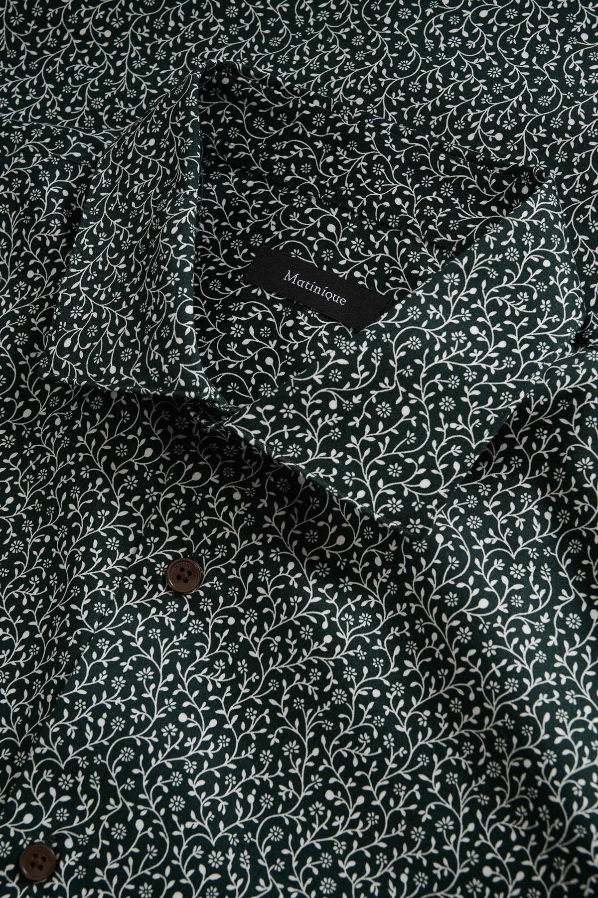 Matinique men's collar detail of dark green floral long-sleeve shirt with white vine print and brown buttons