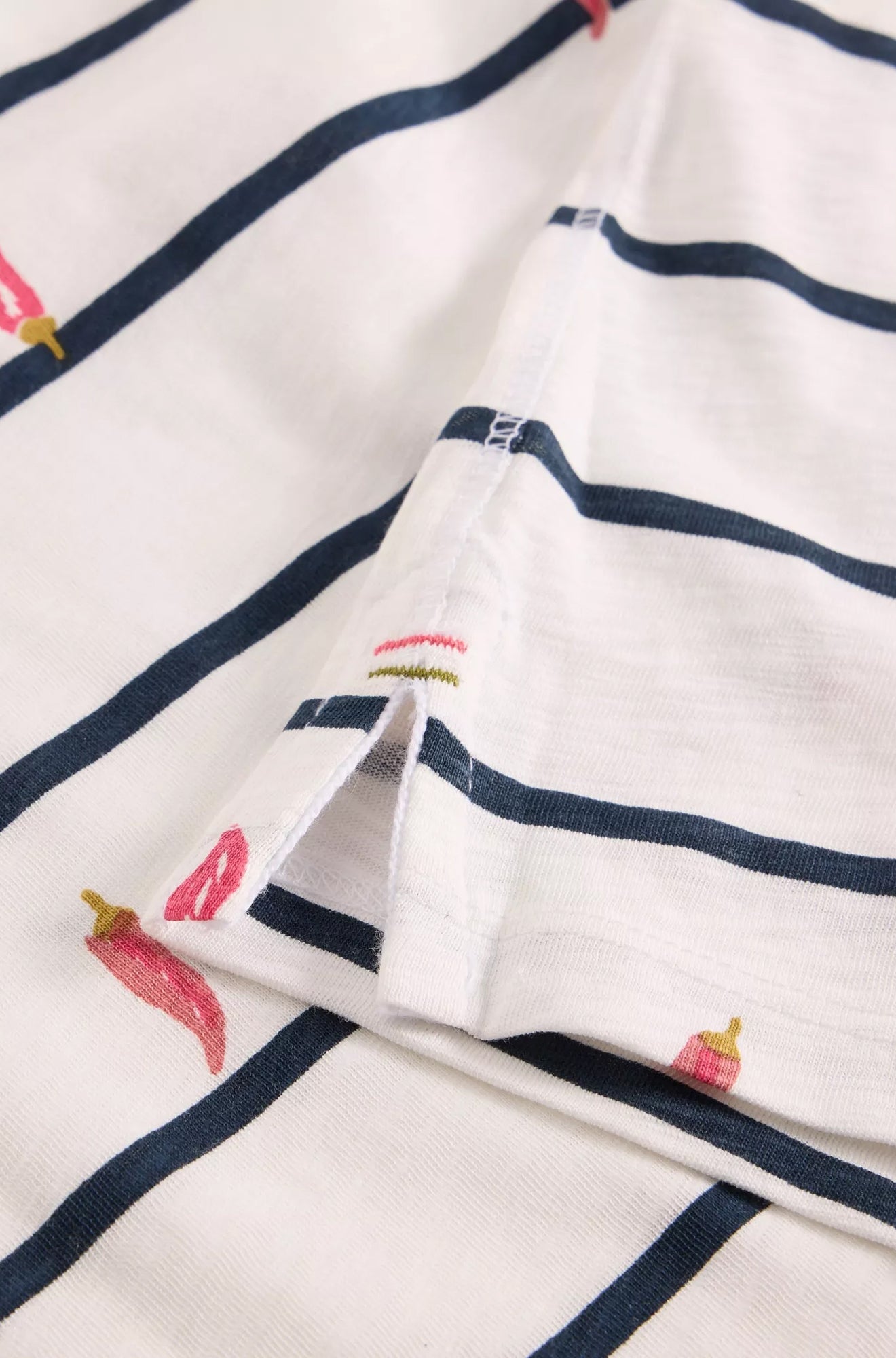Gros plan sur la fente d’ourlet du t-shirt ivoire rayé avec imprimé piments et surpiqûres pour femme par White Stuff