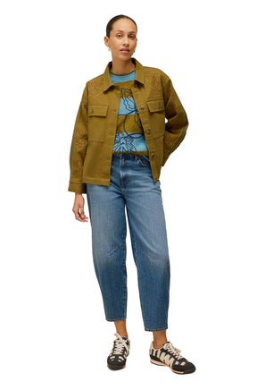 White Stuff women's styled front view of blue and olive striped long-sleeve knit sweater worn under a khaki jacket