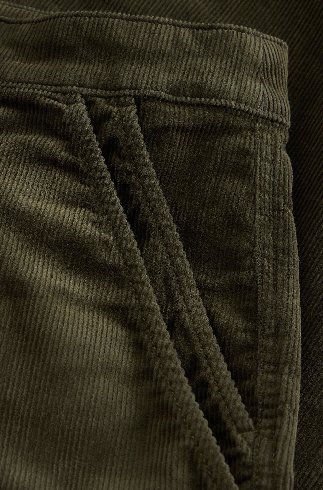 White Stuff women's olive green corduroy pants showing waistband seam and pocket opening, close-up
