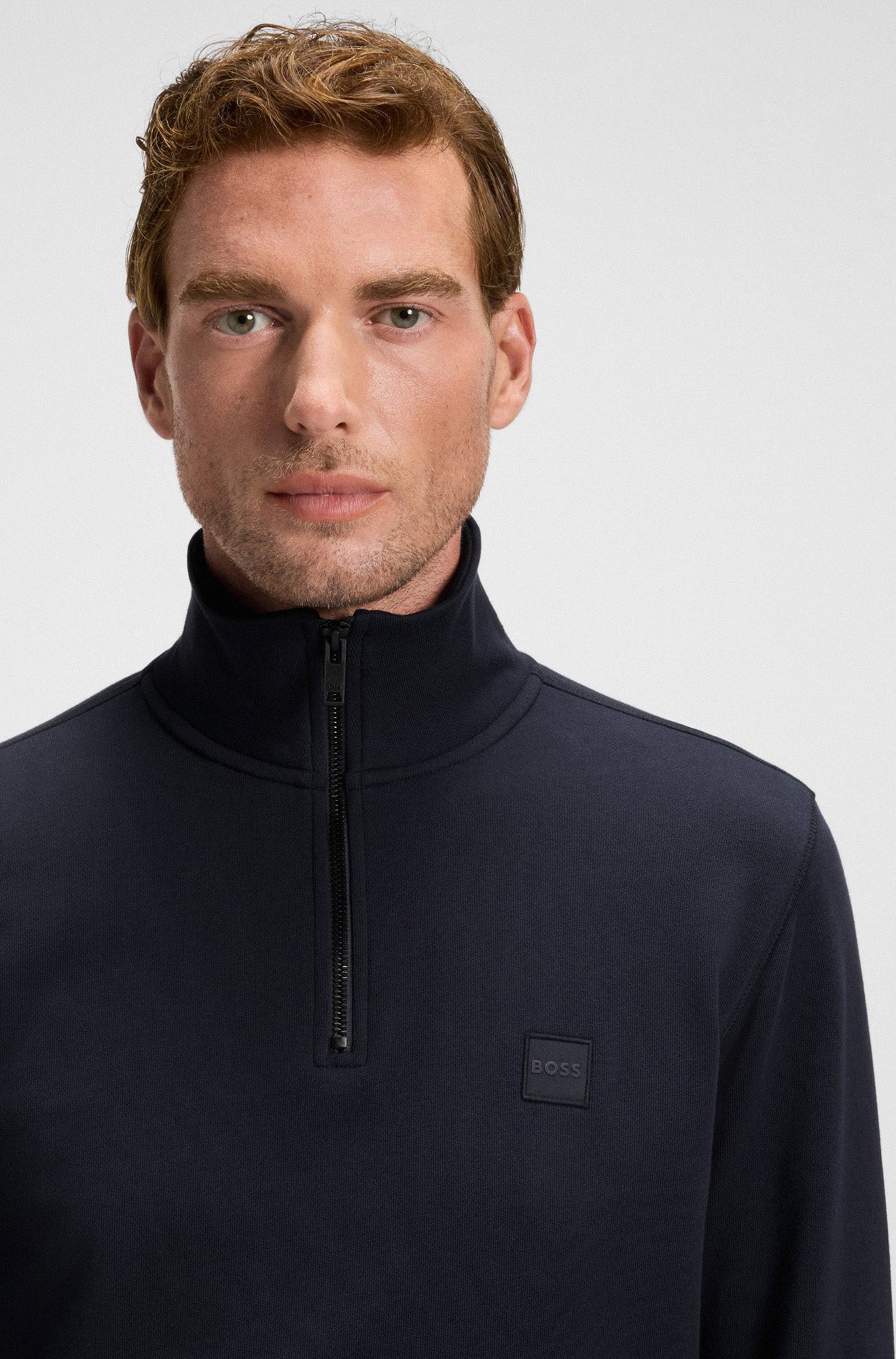 Gros plan du chandail bleu marine à demi-glissière, col montant, fermeture éclair noire et écusson pour homme par HUGO BOSS
