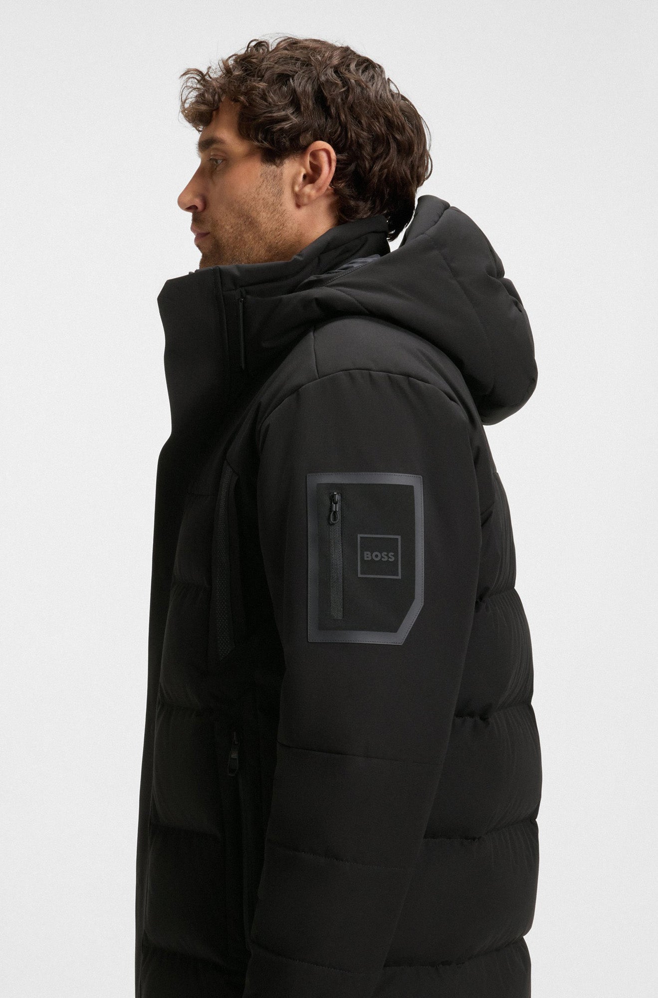 Manteau d’hiver noir à capuchon avec dos matelassé et poche à logo pour homme par HUGO BOSS, vue de côté