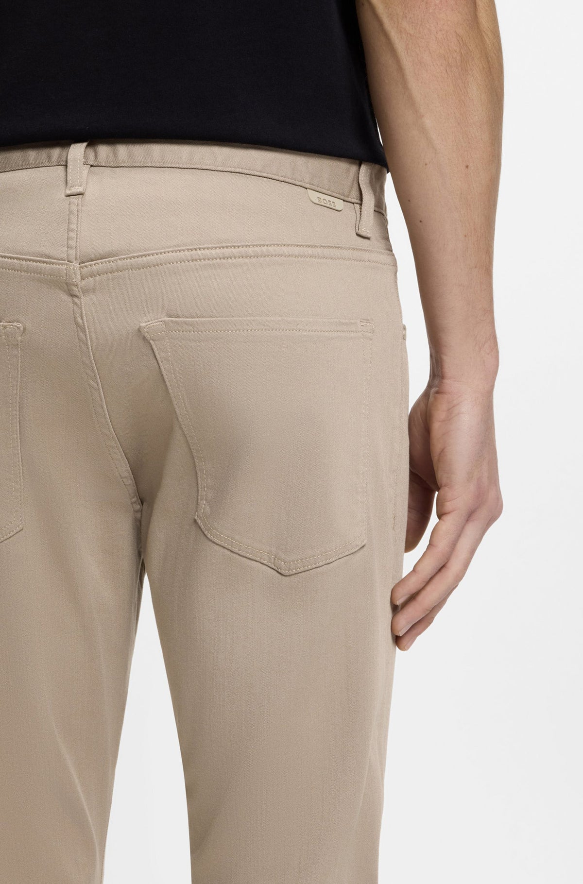 Gros plan arrière sur modèle d’une jean à jambe droite beige avec poches plaquées et languette BOSS pour homme par HUGO BOSS