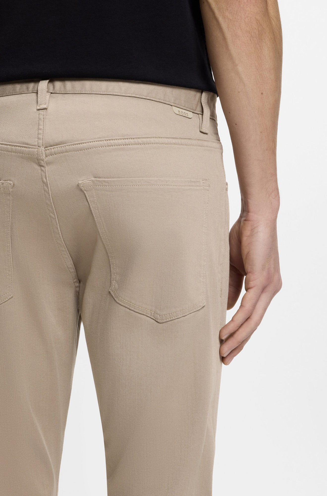 Gros plan arrière sur modèle d’une jean à jambe droite beige avec poches plaquées et languette BOSS pour homme par HUGO BOSS