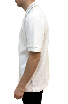 Polo blanc texturé avec col rayé, manche à revers et petit logo latéral pour homme par HUGO BOSS, vue de côté