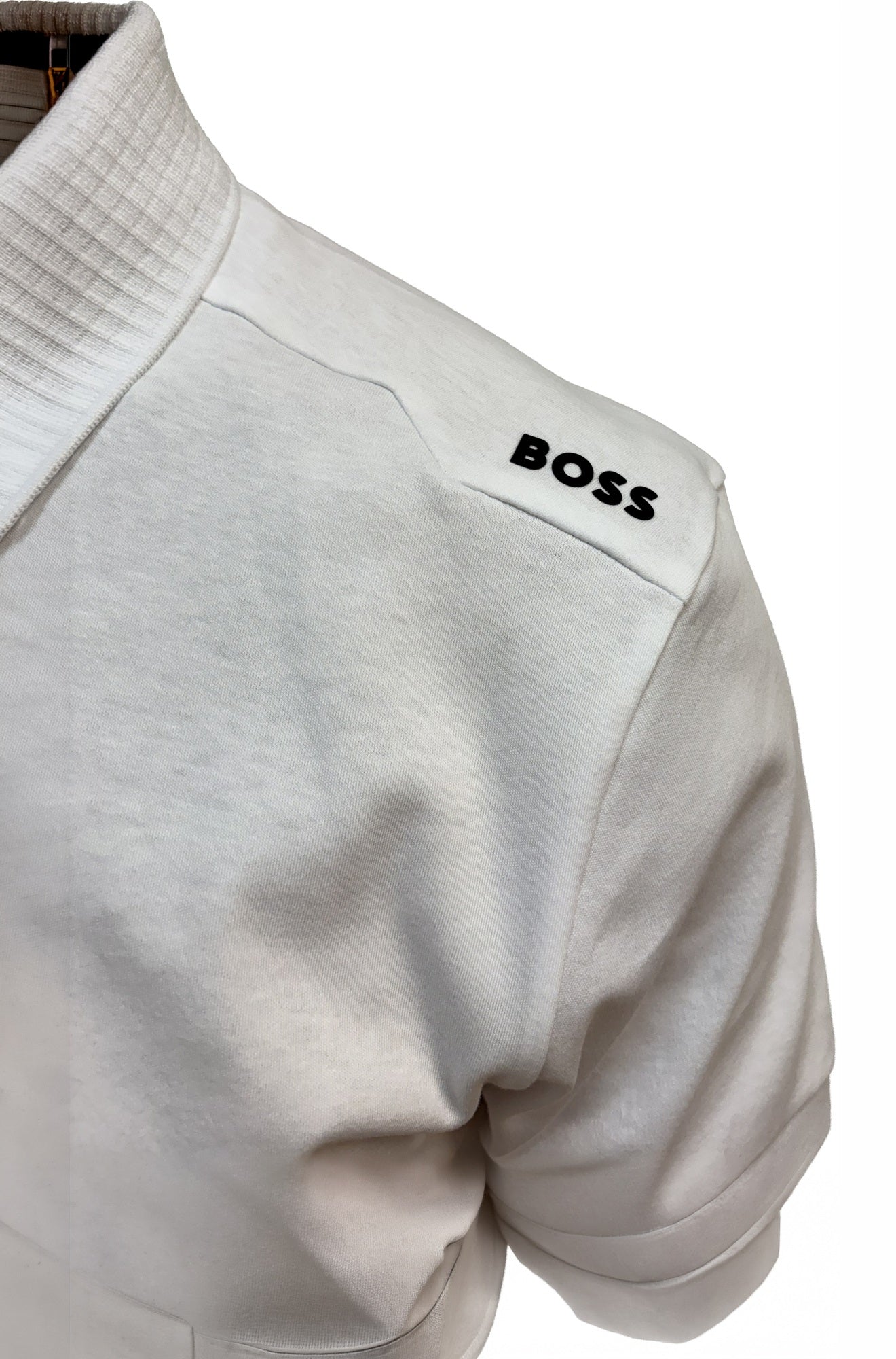 Gros plan sur l’épaule d’un polo blanc avec logo BOSS noir et col côtelé texturé pour homme par HUGO BOSS
