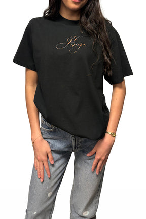 Vue de face rapprochée du t-shirt noir à col rond avec logo Hugo cursif métallique au buste pour femme par HUGO BOSS