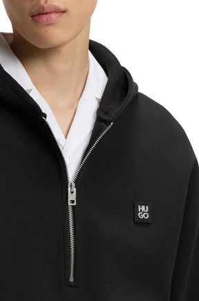 HUGO BOSS men's black half-zip sweatshirt showing silver zipper, hood edge and small HUGO chest patch, close-up
