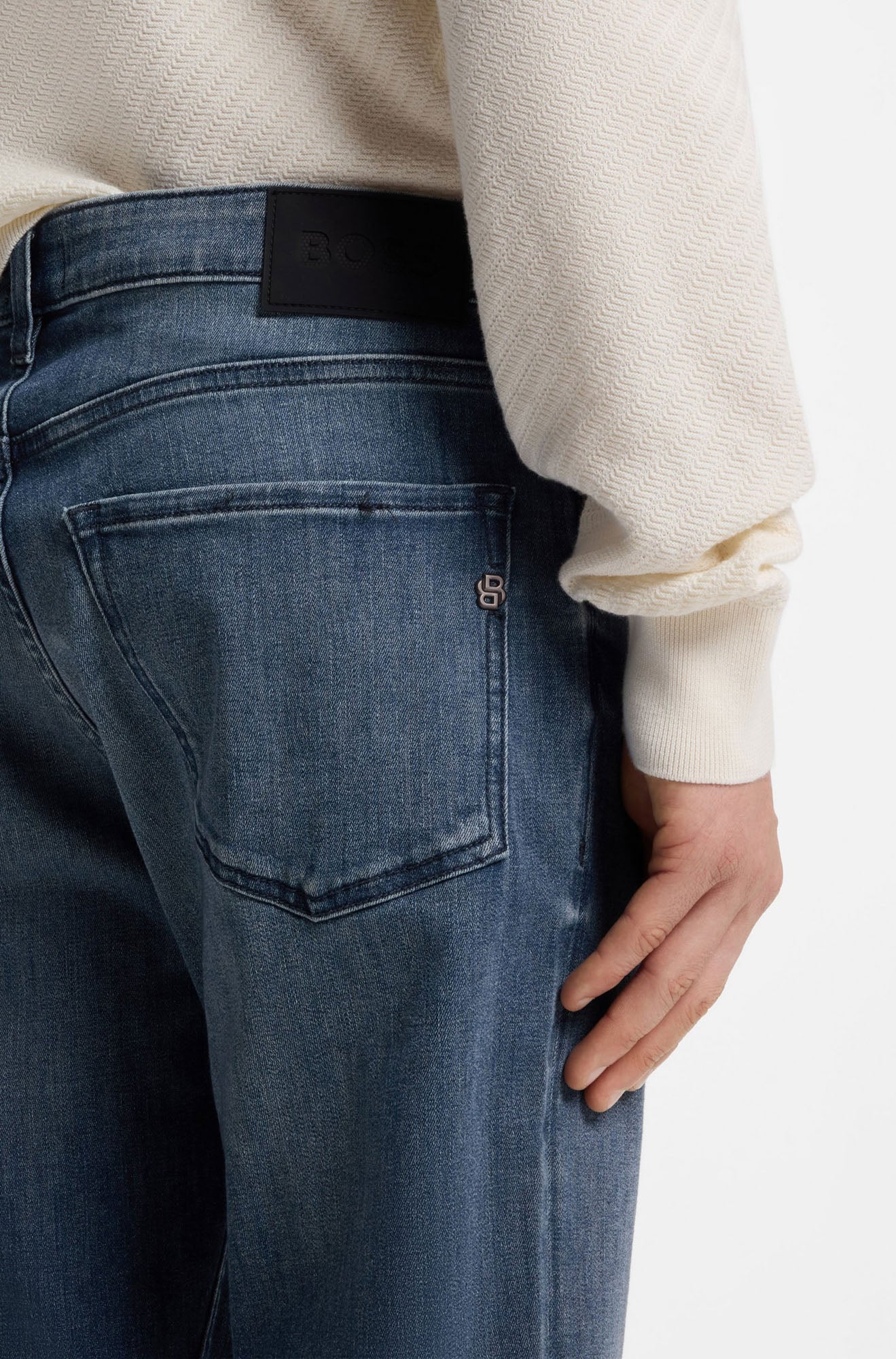 HUGO BOSS men's back model detail of blue washed straight-leg jeans with black waist patch, back pocket and metal B logo