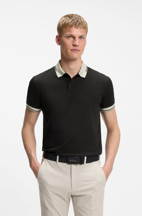 Polo noir porté de face avec col ivoire, poignets rayés et logo ton sur ton pour homme par HUGO BOSS