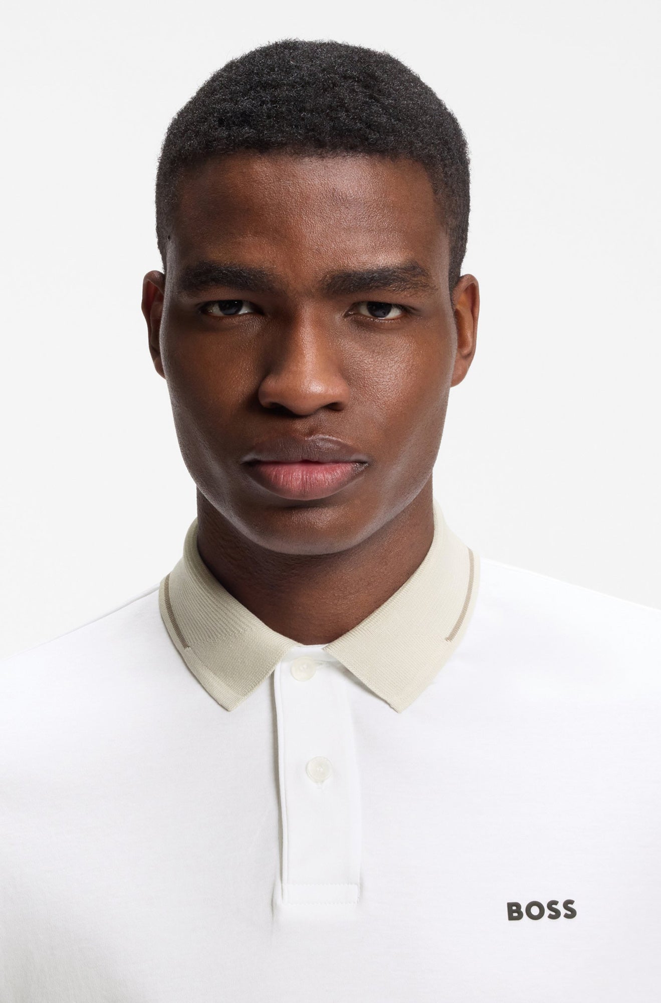Gros plan du polo blanc montrant le col beige, la patte boutonnée et le logo BOSS pour homme par HUGO BOSS